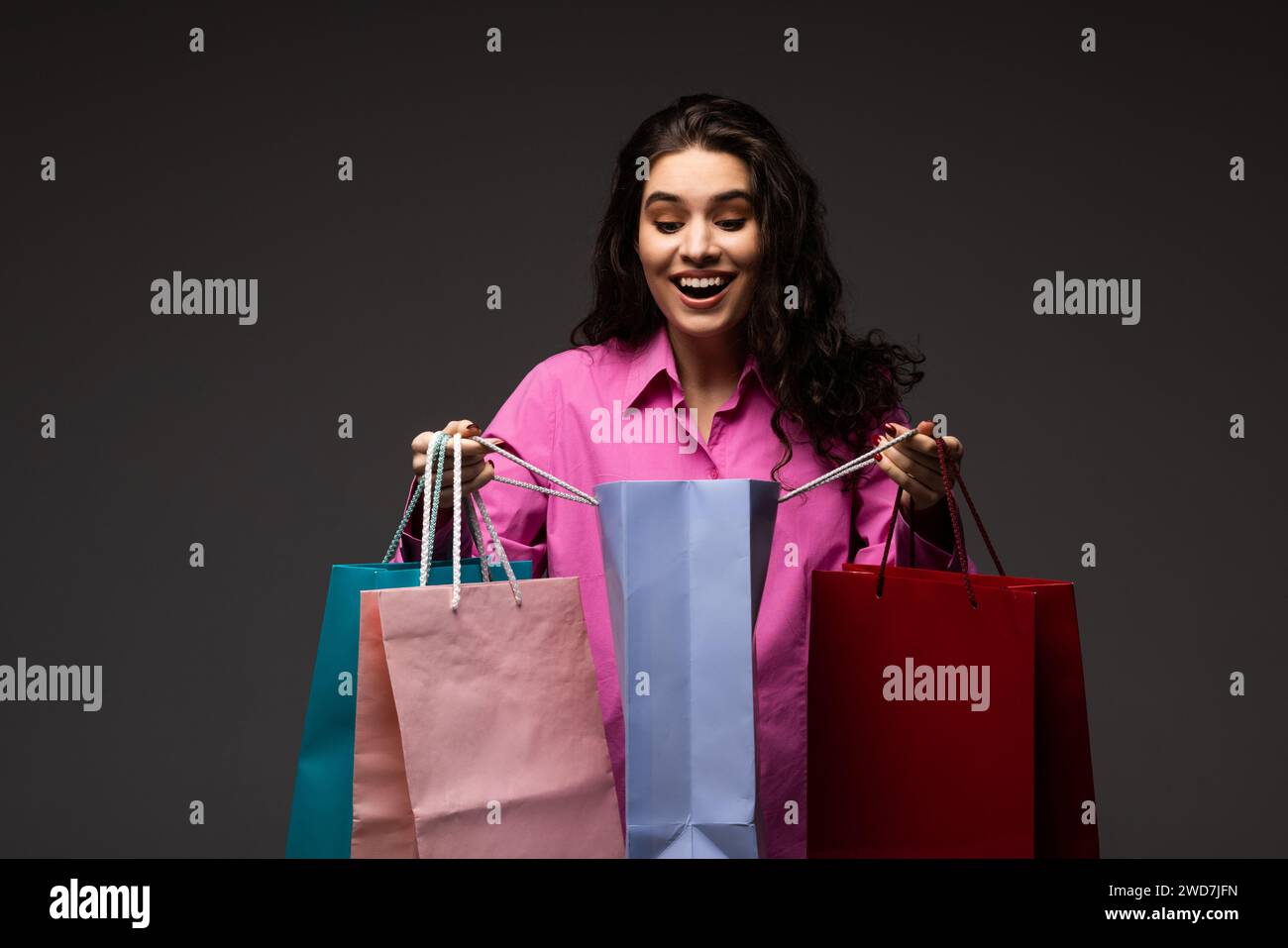 Woman holding shopping bags against a grey background Stock Photo