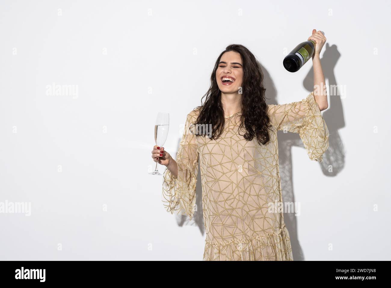 Woman in dress drinking champagne from bottle isolated on a white background Stock Photo