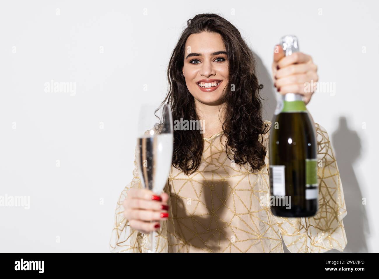 Cheerful elegant woman having fun on party, celebrating something, dancing with bottle and glass of champagne, standing over white background Stock Photo