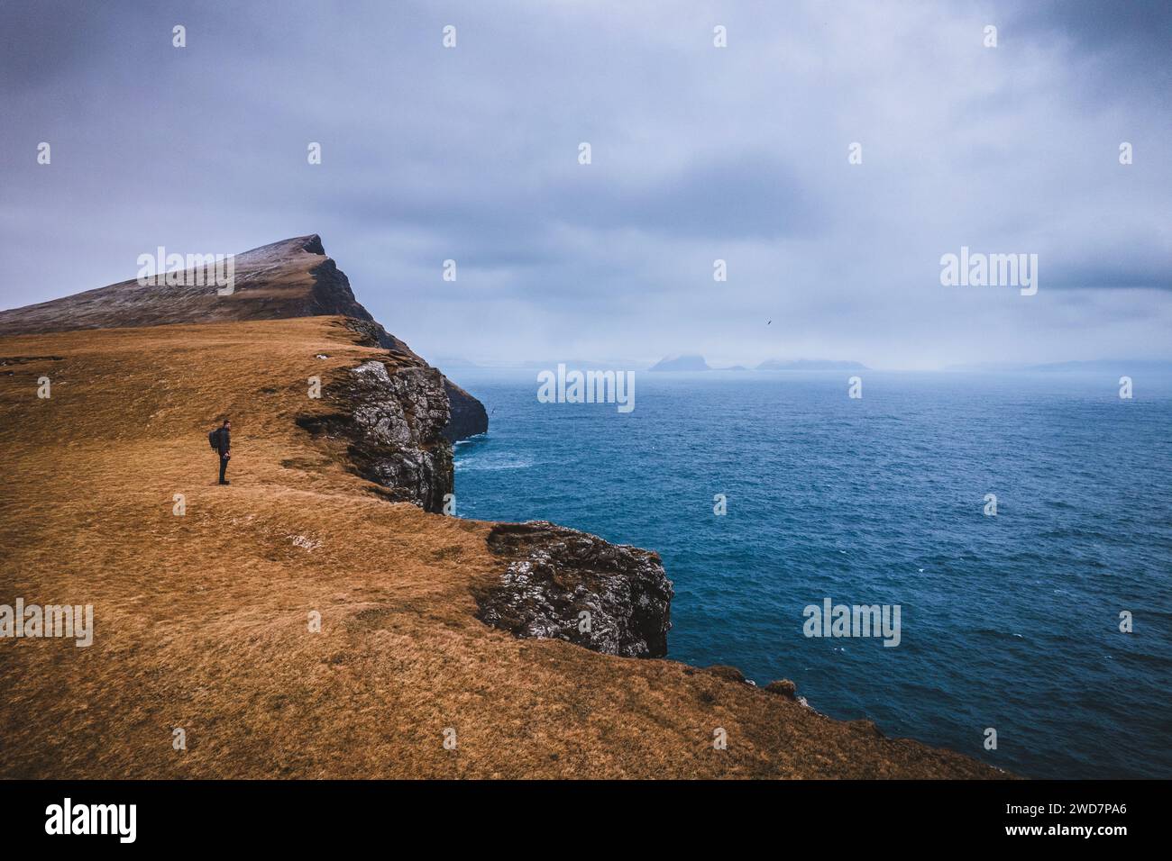 Man with backpack hikes along cliff in the Faroe Islands Stock Photo