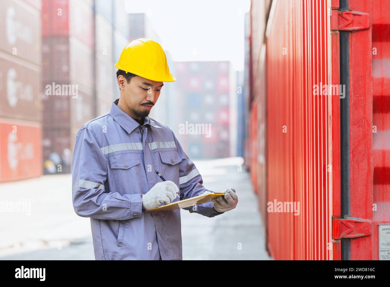 Japanese male smart worker working in container port cargo. Japan shipping logistics industry customs staff. Stock Photo