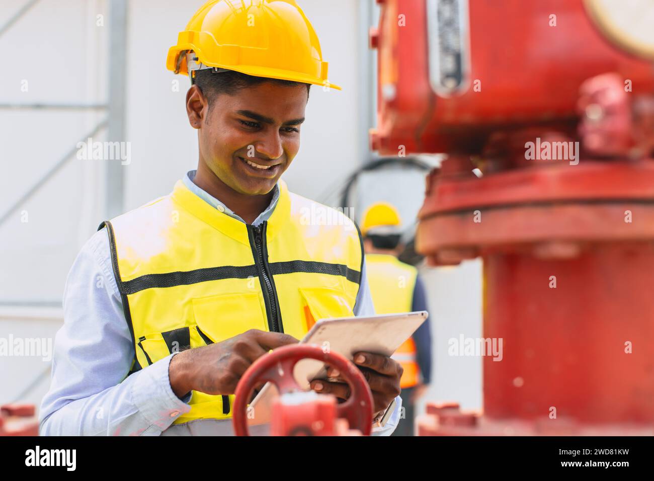 happy indian engineer safety staff worker work control operate valve gas pipe oil industry Stock Photo