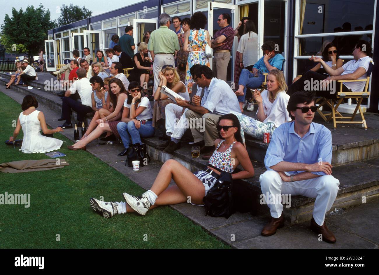 1980s UK fashion a young woman wearing British Knights - BK urban fashion trainers, a cropped top and stylish stripped 1970s hot pants, black leather gloves and matching leather handbag. Dark glasses were de rigueur for the wealthy, casual polo groupies frequenting the Guards Polo Club in Windsor Great Park. Windsor, Berkshire, England circa June 1985 HOMER SYKES Stock Photo