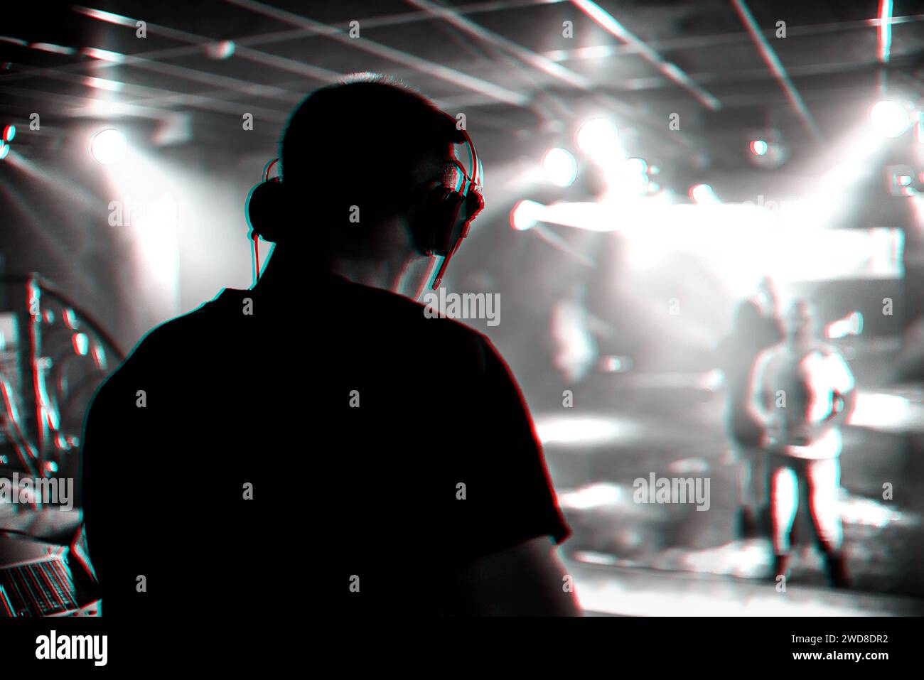 DJ mixes music in a nightclub with people dancing on the dance floor. Black and white photo with glitch effect and small grain Stock Photo