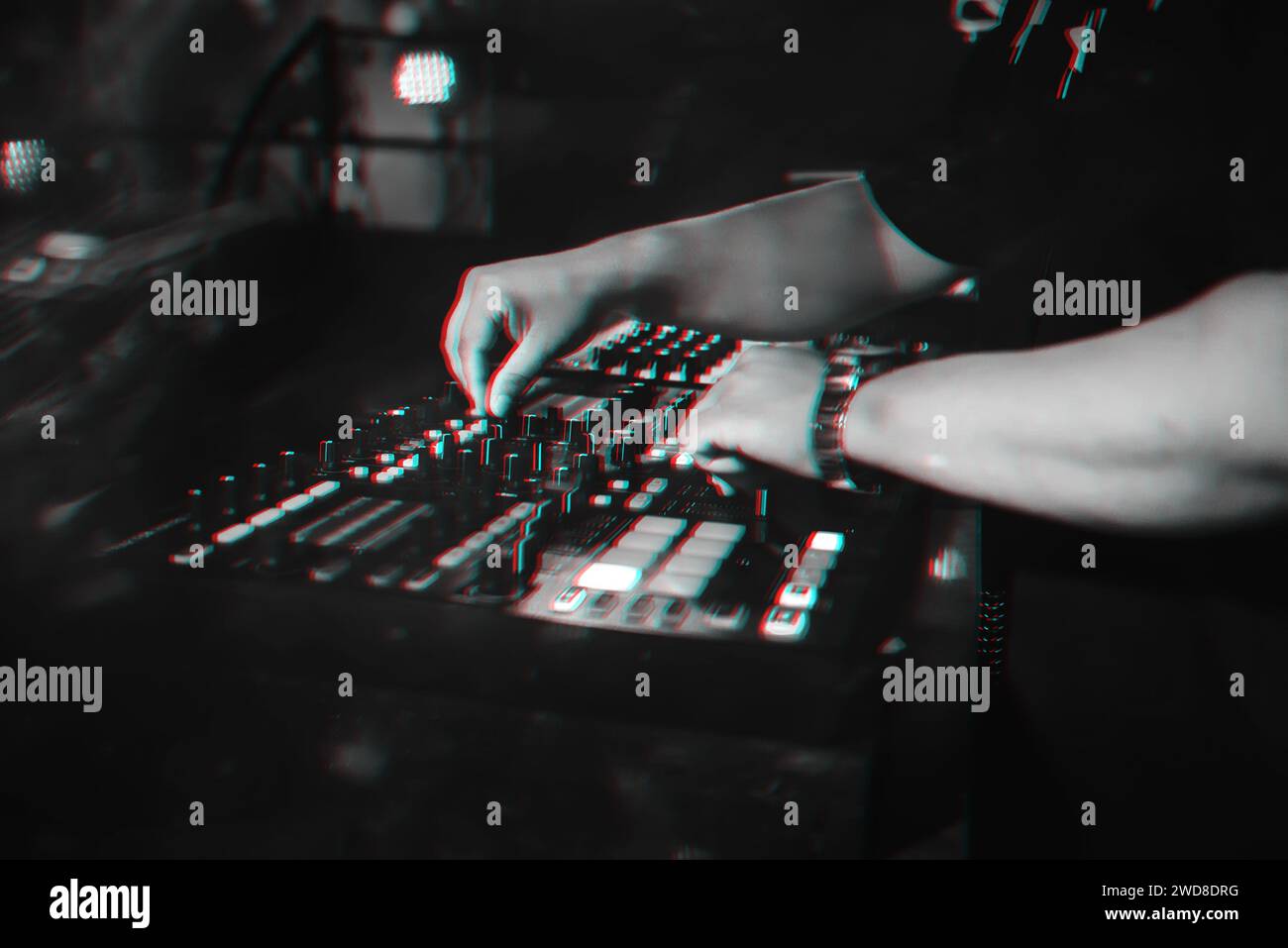 DJ plays with his hands on a music mixer in a nightclub. Black and white photo with glitch effect and small grain Stock Photo