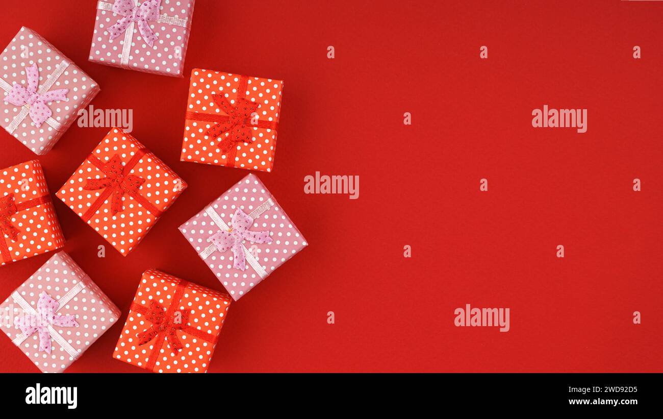 Red and pink small gift boxes on red background with copy space. Banner ...