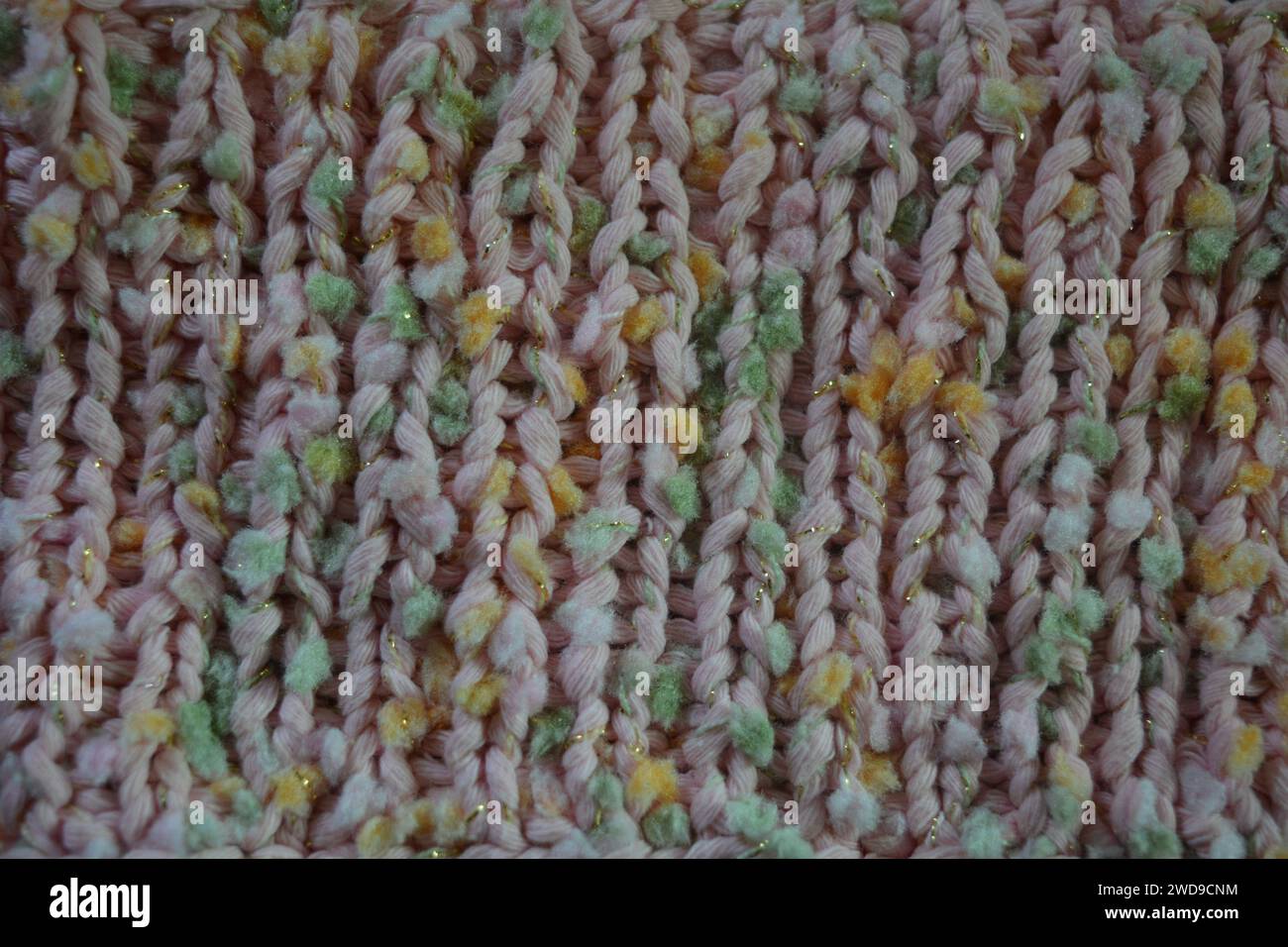 Hand weaving, knitting. A beautiful patterned background is knitted from pink threads with colored inserts. Stock Photo