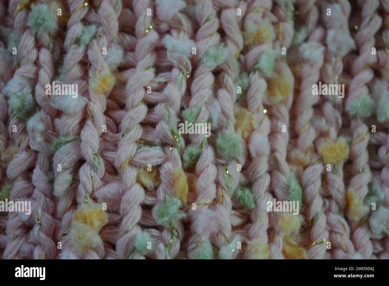 Hand weaving, knitting. A beautiful patterned background is knitted from pink threads with colored inserts. Stock Photo