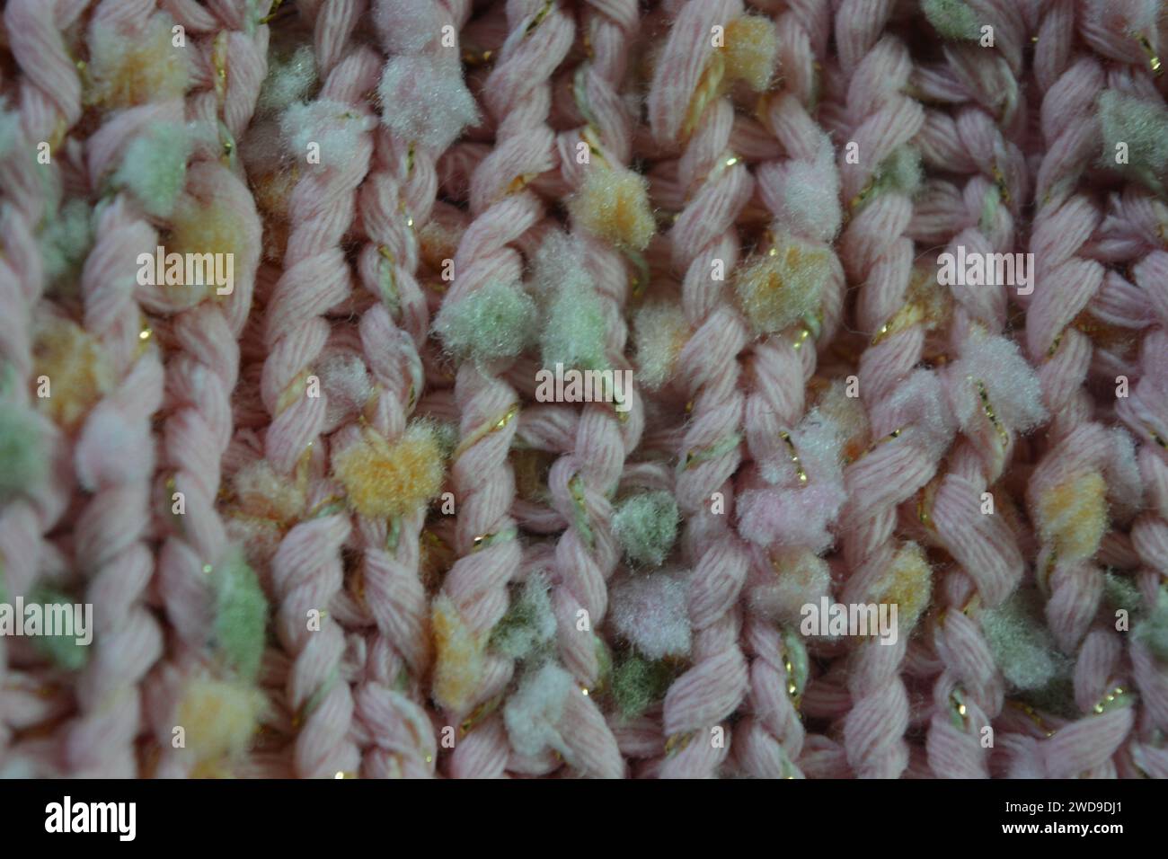Hand weaving, knitting. A beautiful patterned background is knitted from pink threads with colored inserts. Stock Photo