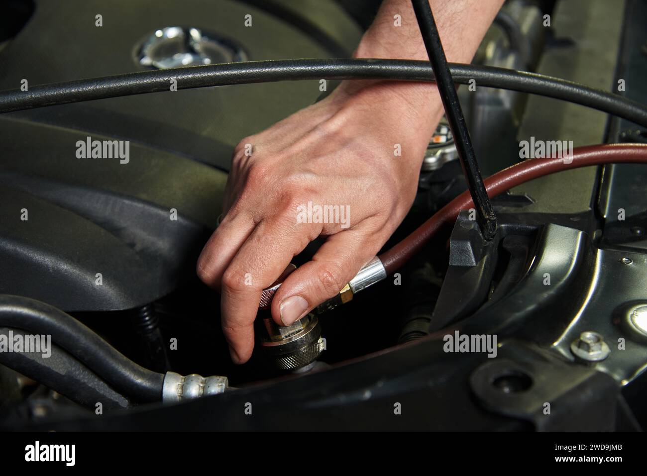 Hands of the master in cars and various car parts. Car engine, bumper, metal parts of the car. The master makes a car repair in a car repair shop. Stock Photo