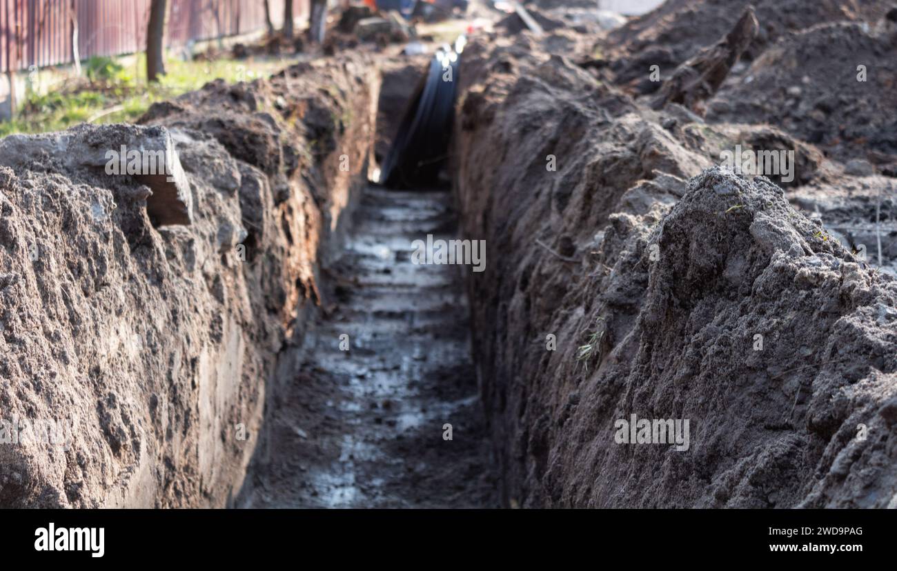 Earthwork. A deep long trench dug in the ground for laying cables, pipes. Stock Photo