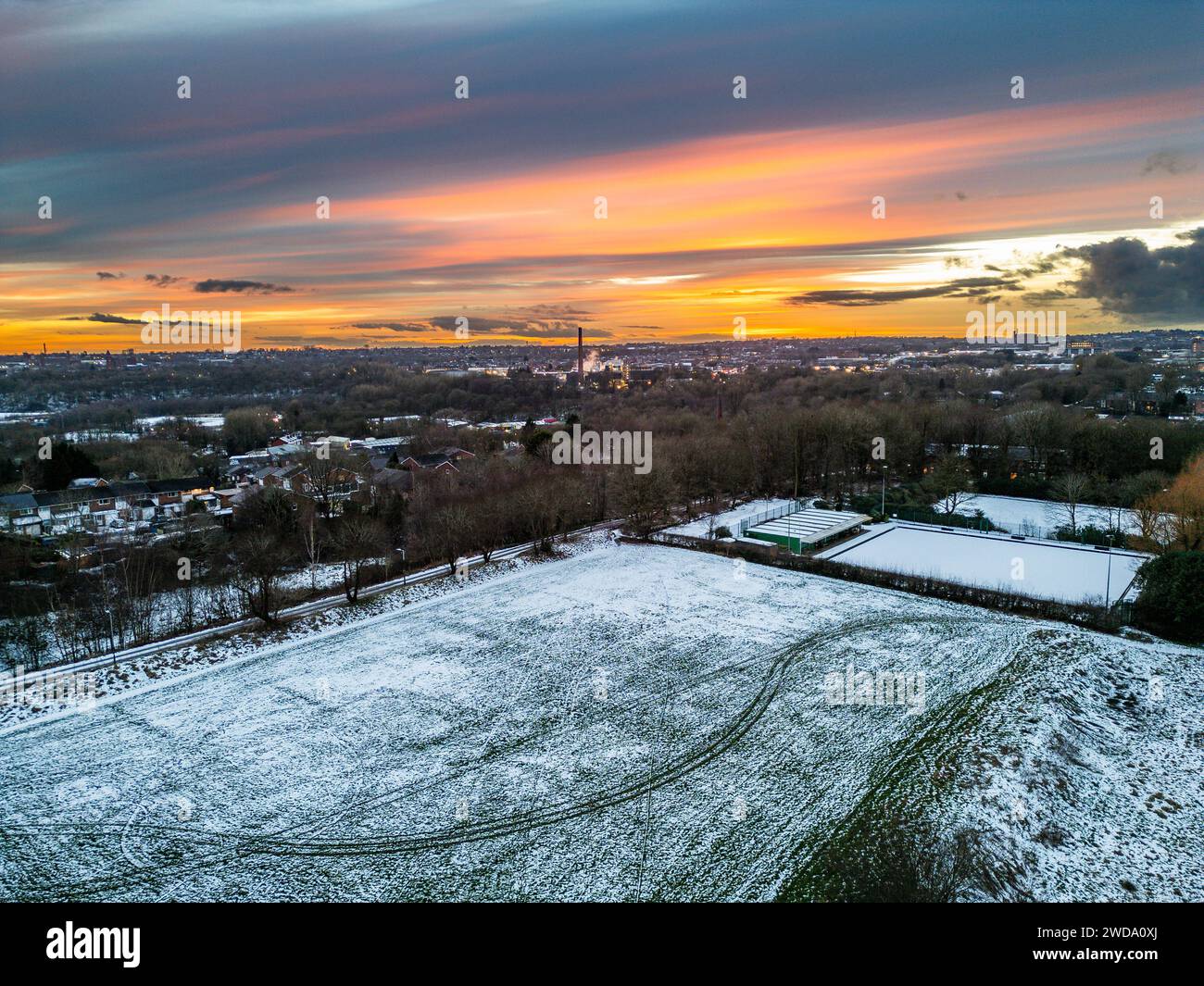 Bolton, England, UK, Friday January 19, 2024. Drone images of tonights fiery sunset over a frozen Leverhulme Park and showing the lights of Bolton town centre in the background. Credit: Paul Heyes/Alamy News Live. Stock Photo