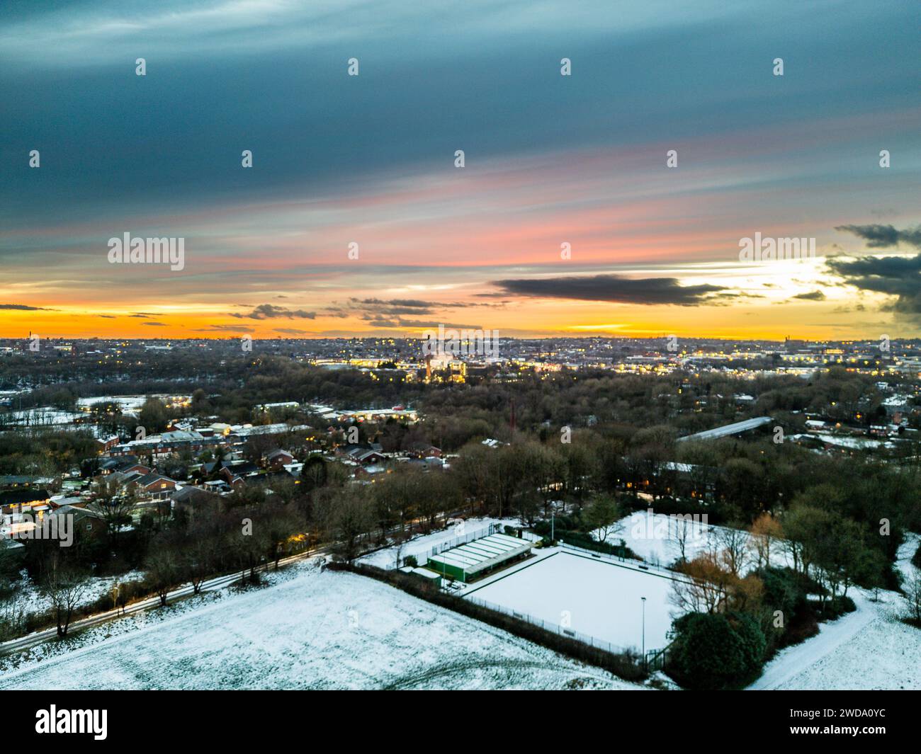 Bolton, England, UK, Friday January 19, 2024. Drone images of tonights fiery sunset over a frozen Leverhulme Park and showing the lights of Bolton town centre in the background. Credit: Paul Heyes/Alamy News Live. Stock Photo
