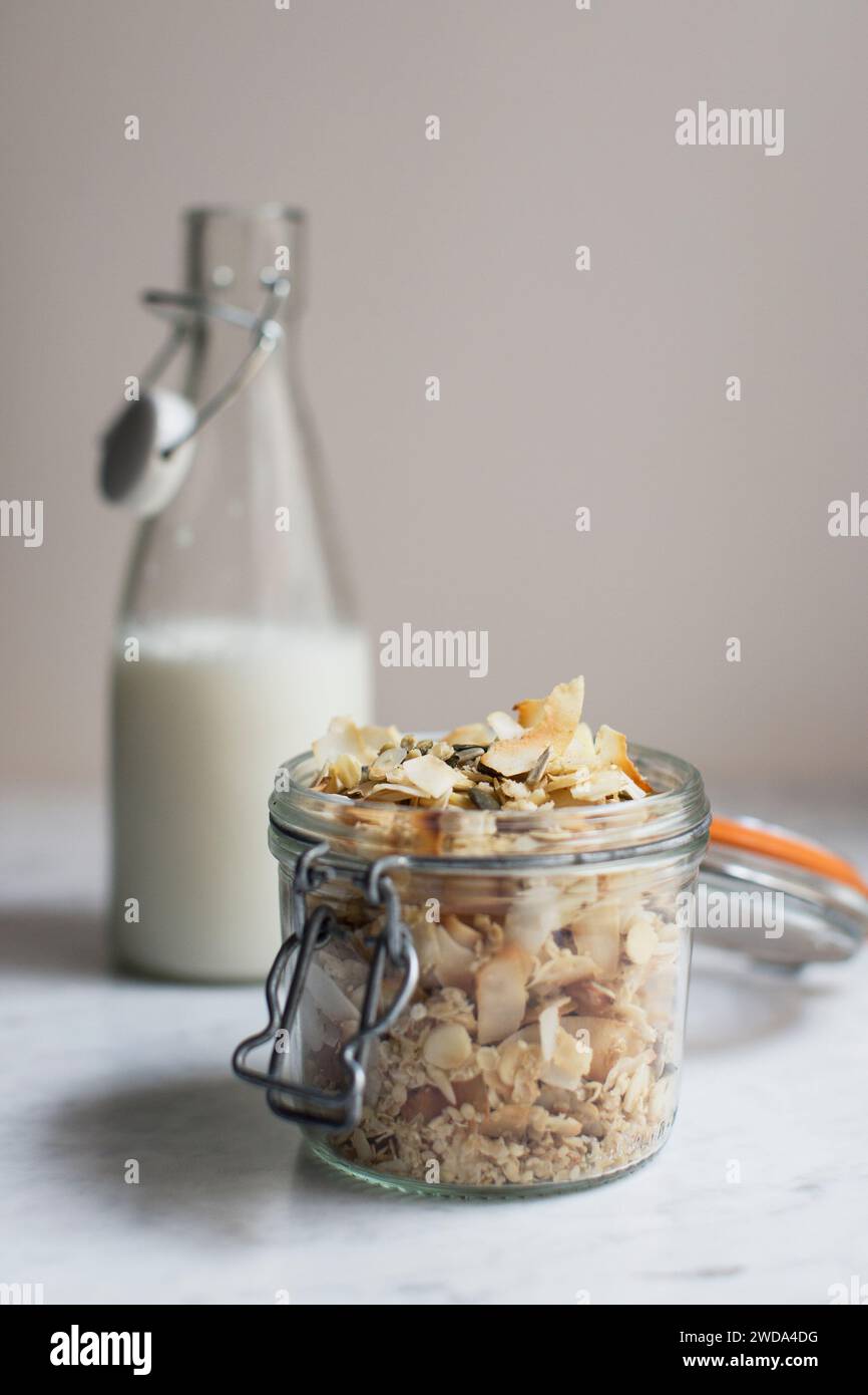 Home made granola in a jar with glass bottle of milk Stock Photo