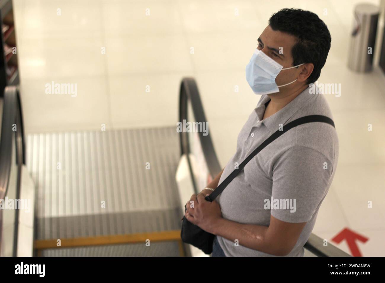 Latino man with protection mask on escalators in shopping mall, new ...