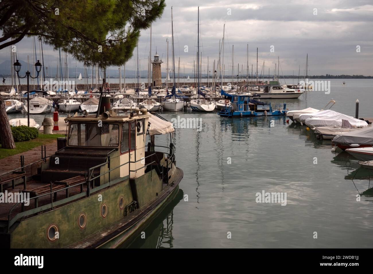DESENZANO DEL GARDA, ITALY - SEPTEMBER 21, 2023:   View of Lighthouse (Faro di Desenzano del Garda) and boats in the harbour Stock Photo