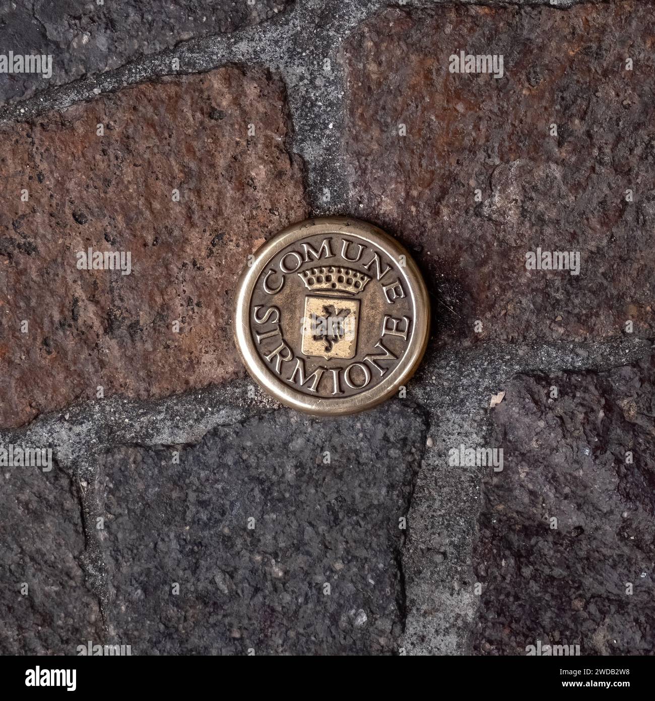 SIRMIONE, ITALY - SEPTEMBER 21, 2023:  Metal stud in pavement with text for Sirmione Commune and Coat of Arms Stock Photo