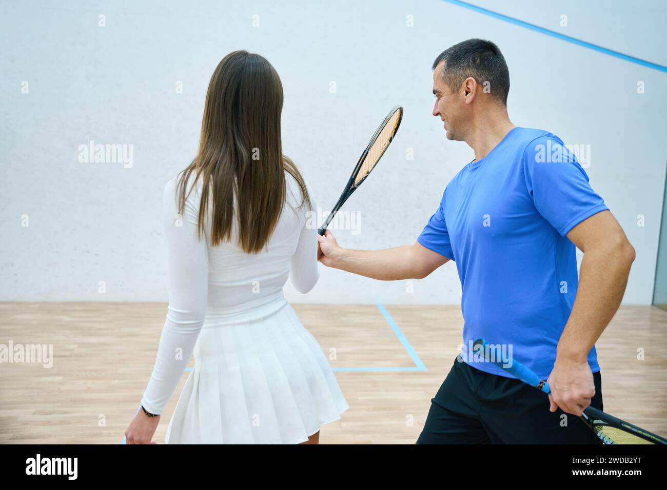 Dedicated man instructor guides player through squash lesson focusing