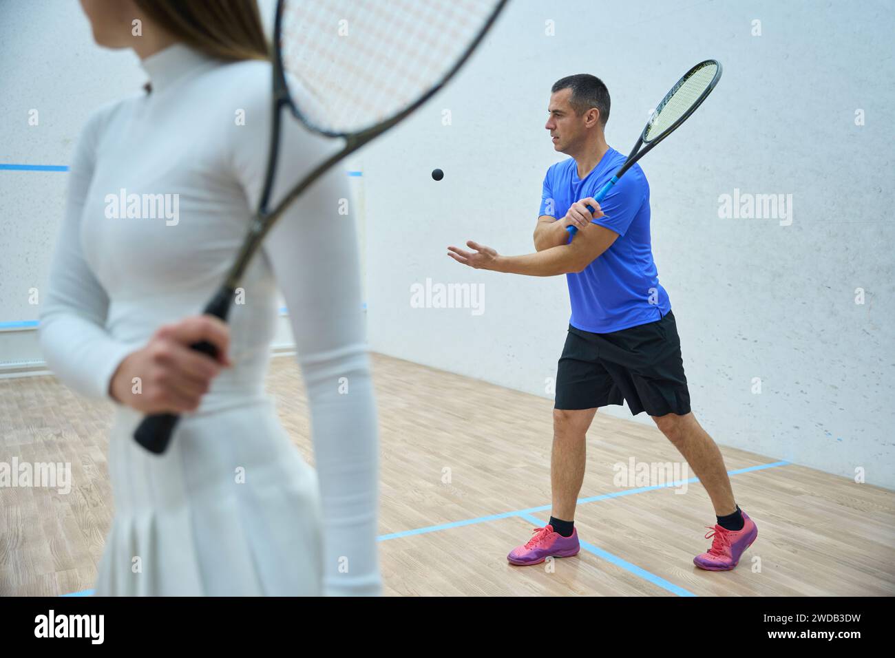 Enthusiastic man coach teaching woman accurate racket skills in squash ...