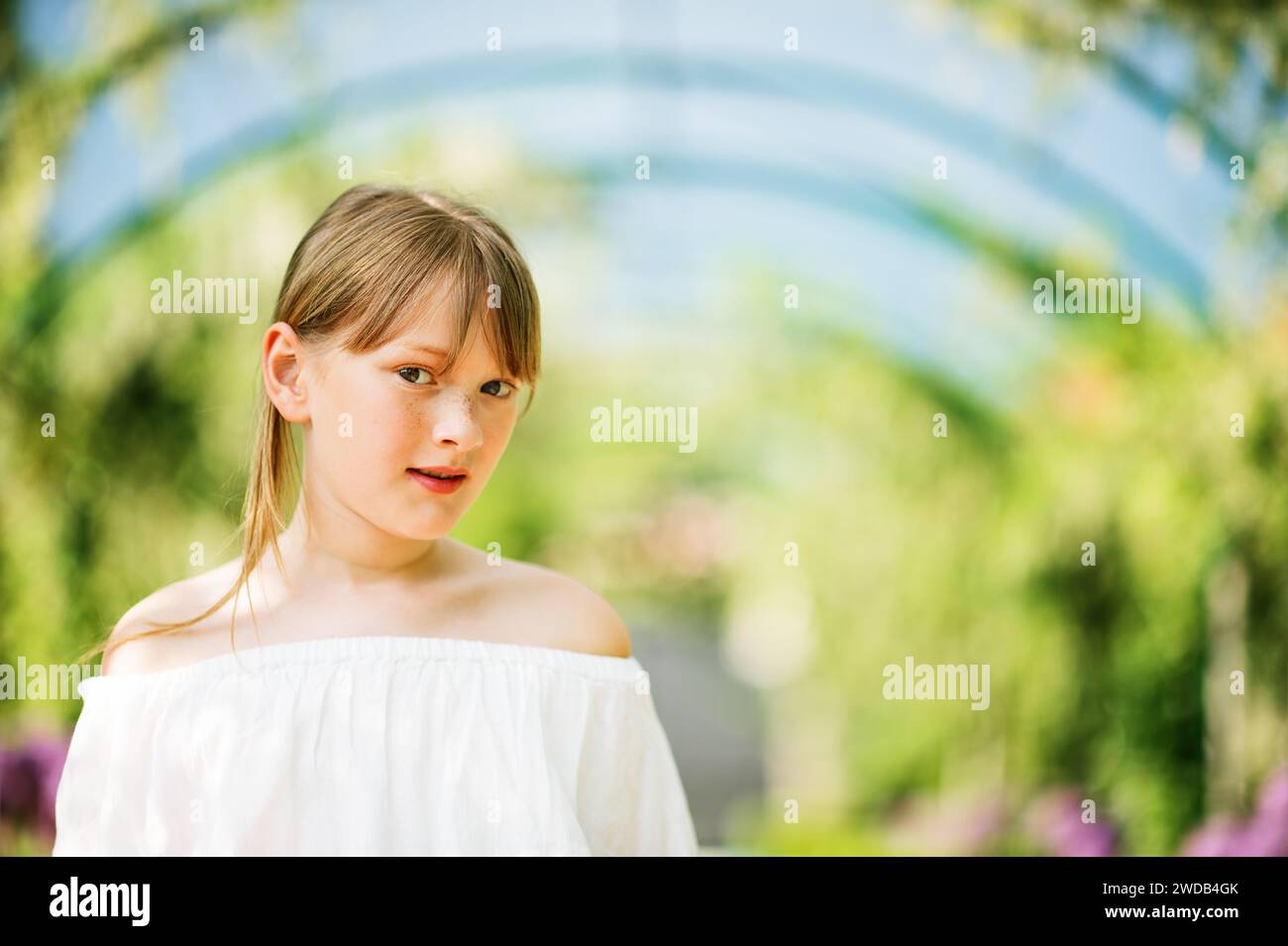 Outdoor close up portrait of a cute 9-10 year old little girl in a beautiful park with an arch Stock Photo