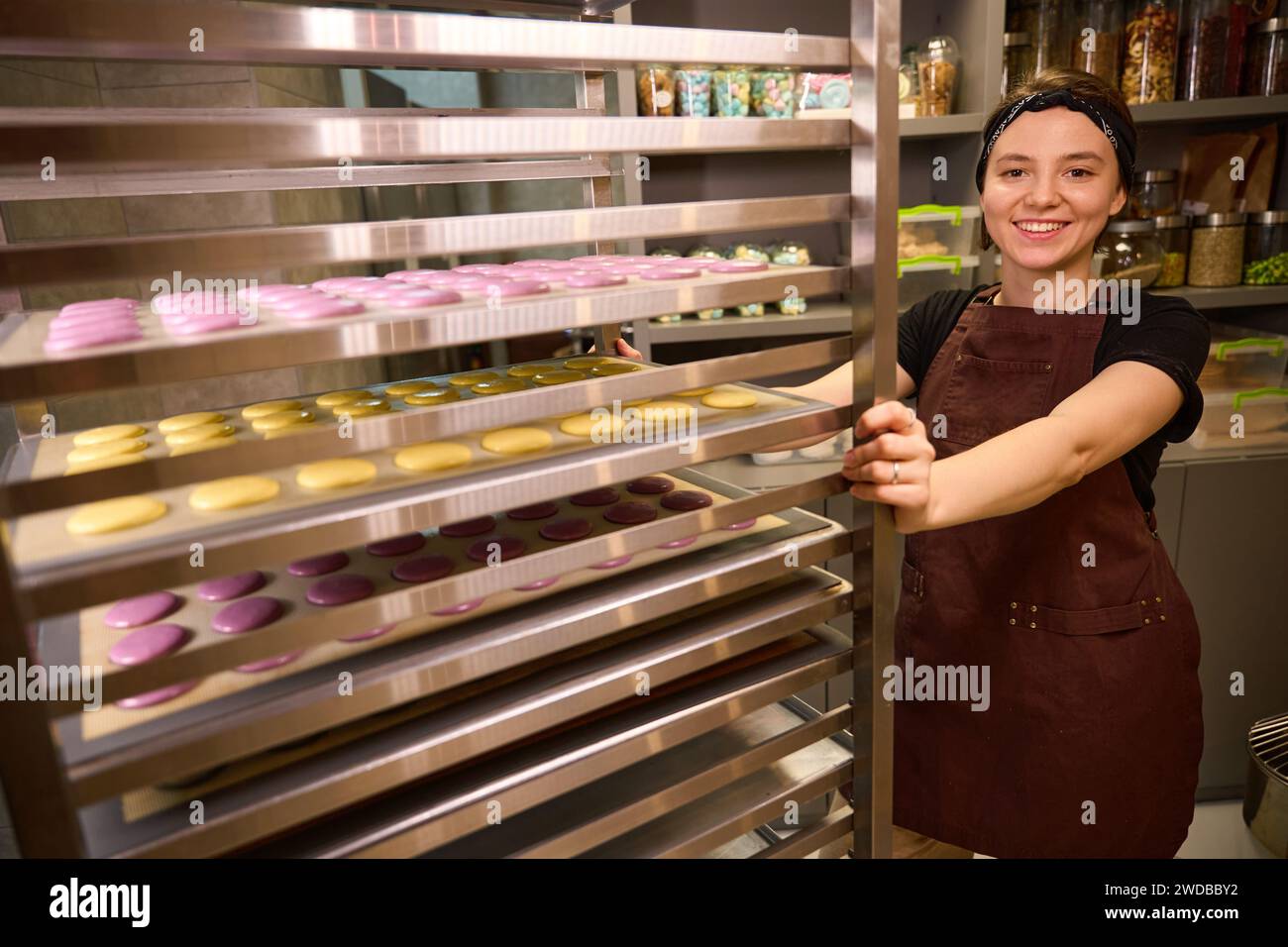 Joyous pastry chef posing for camera with batch of biscuits Stock Photo