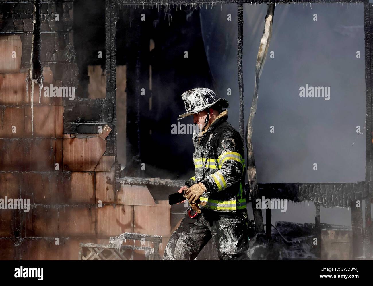 A firefighter looks for hotspots in the steaming shell of a home after