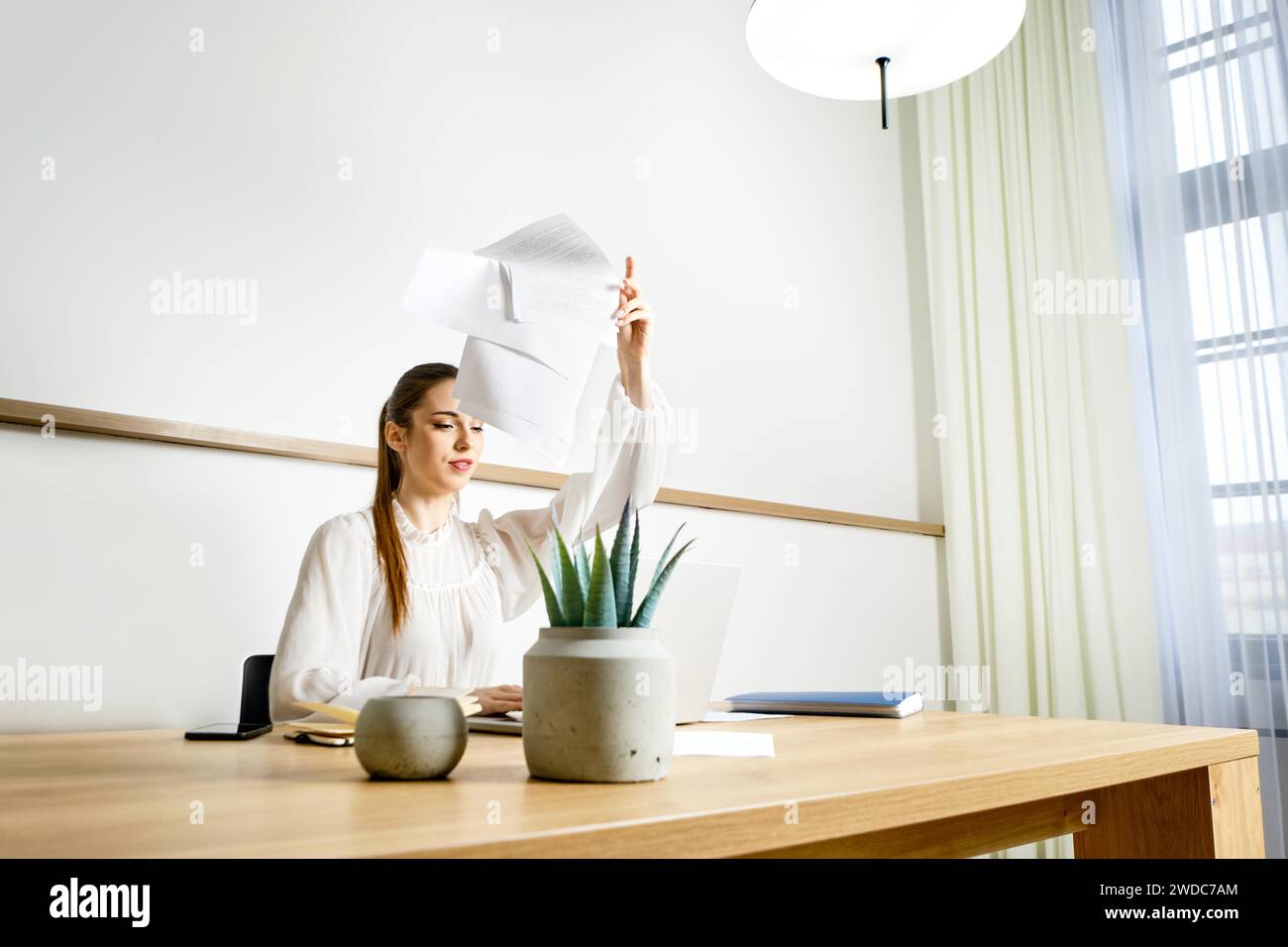 A woman is tired of monotonous work in the office and throws away documents Stock Photo