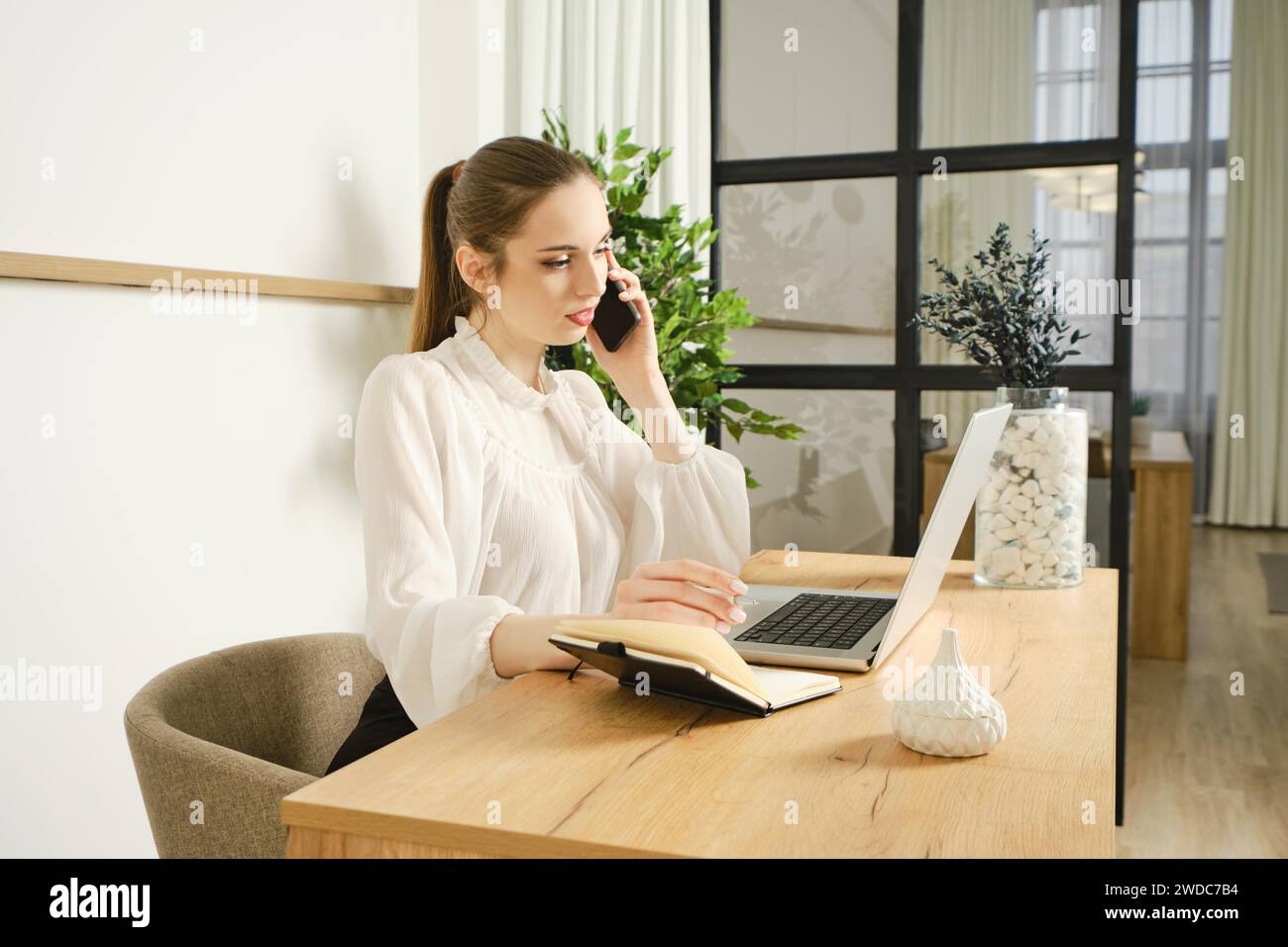 A young woman advises a client by phone, gives information and provides support Stock Photo