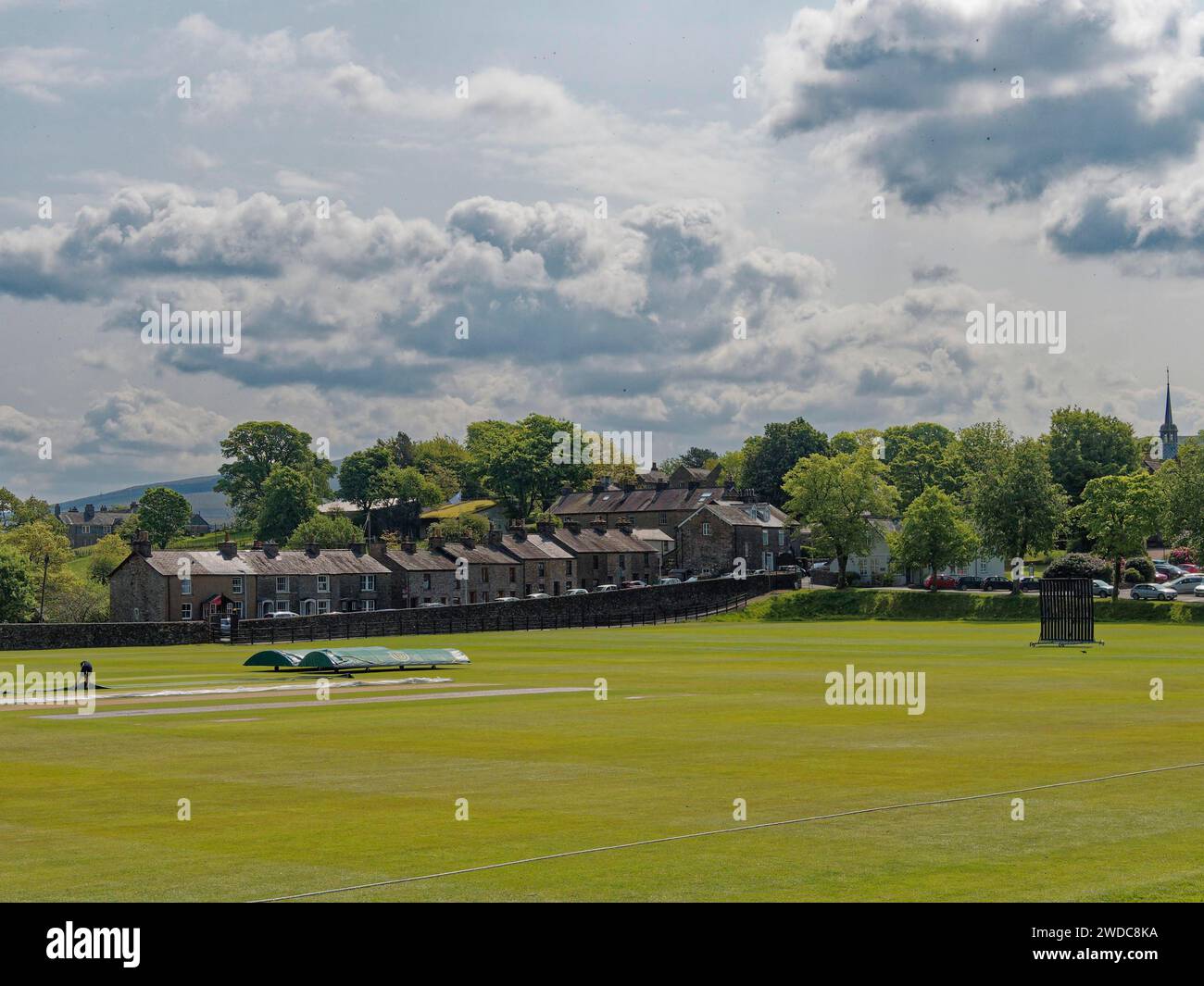 View across a quiet meadow to a row of houses under a partly cloudy sky