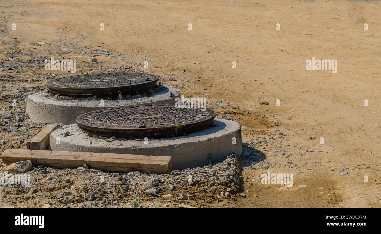 Two steel manhole covers on new concrete manholes at new rural construction site, South Korea, South Korea Stock Photo