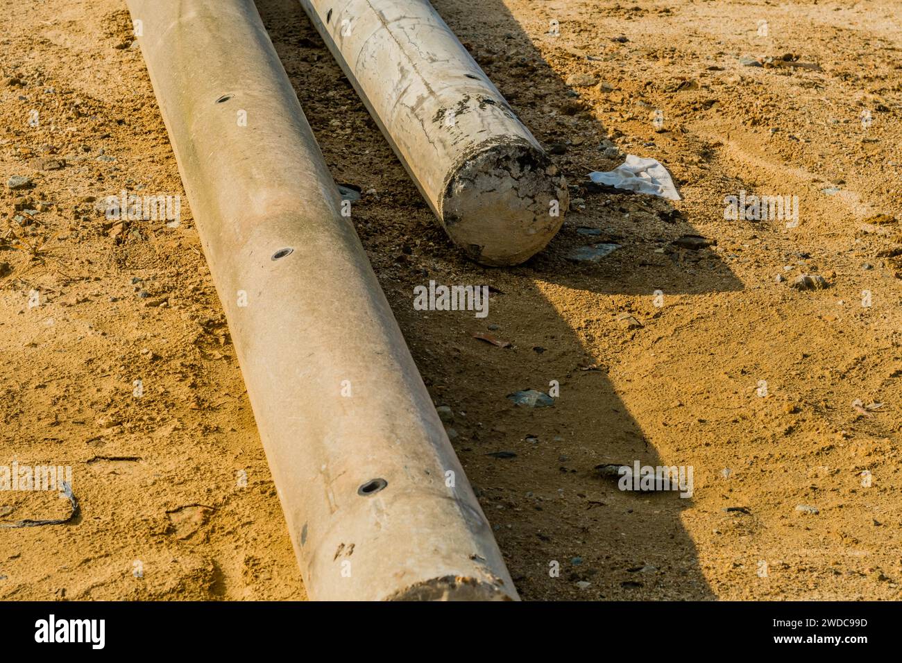Pole In Ground Closeup of concrete utility poles laying on ground at new construction ...
