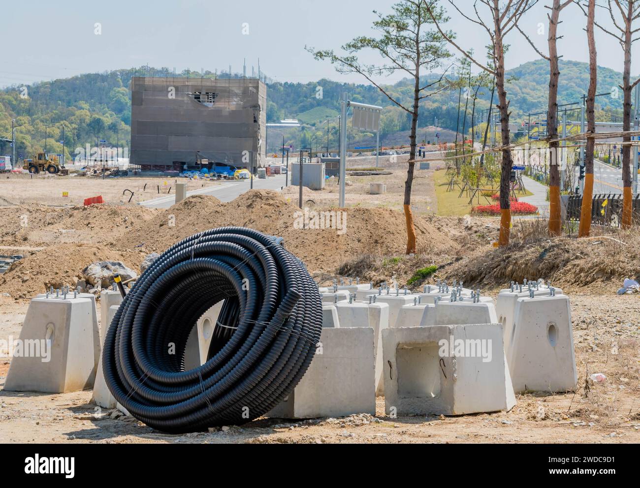 Daejeon, South Korea, April 18, 2021: Large roll of flexible PVC pipe leaning against concrete lamppost bases at construction site, South Korea Stock Photo