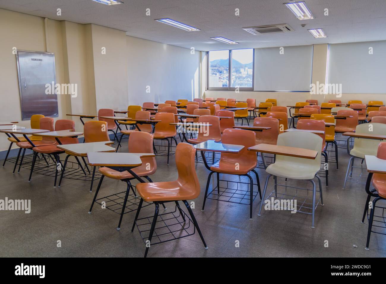 Classroom with empty desks arranged haphazardly with lights turned on