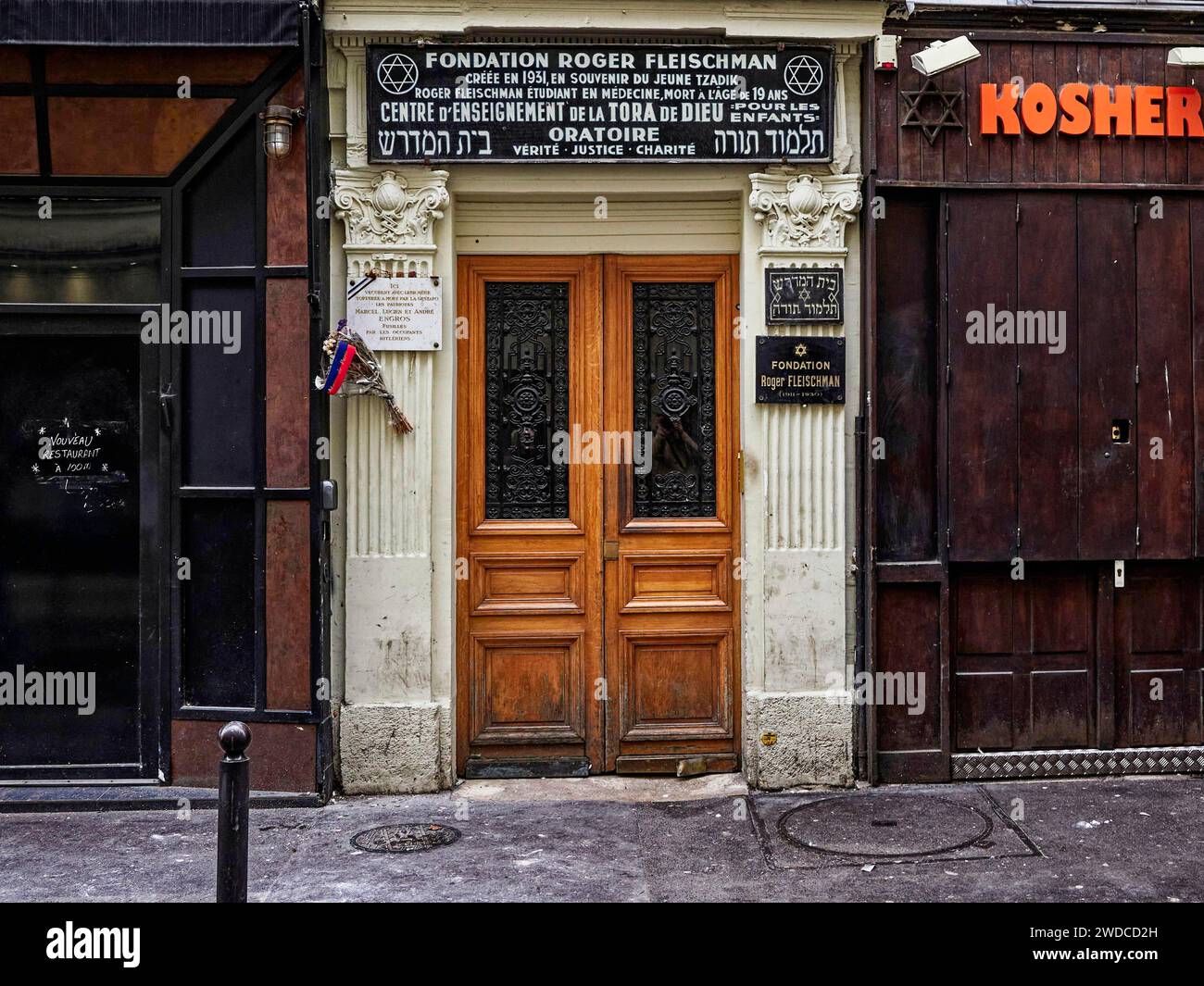 Traditional wooden door of a Jewish shop with kosher signs in a city street, synagogue entrance. Paris Stock Photo
