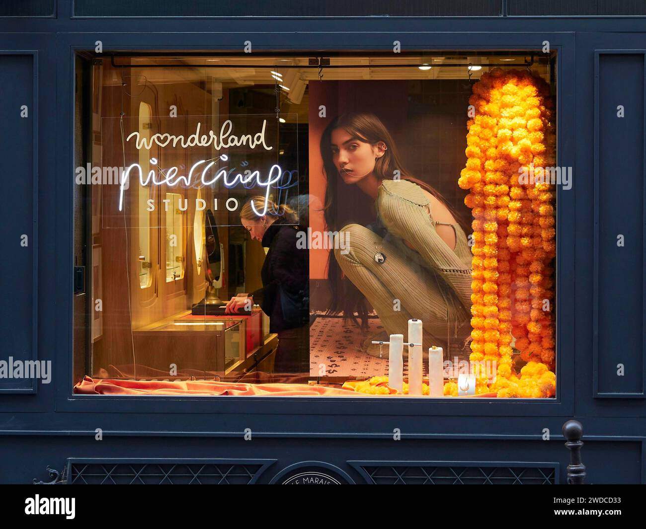 A shop window of a fashion shop illuminated with warm lights and an advert with a woman on it. Paris Stock Photo