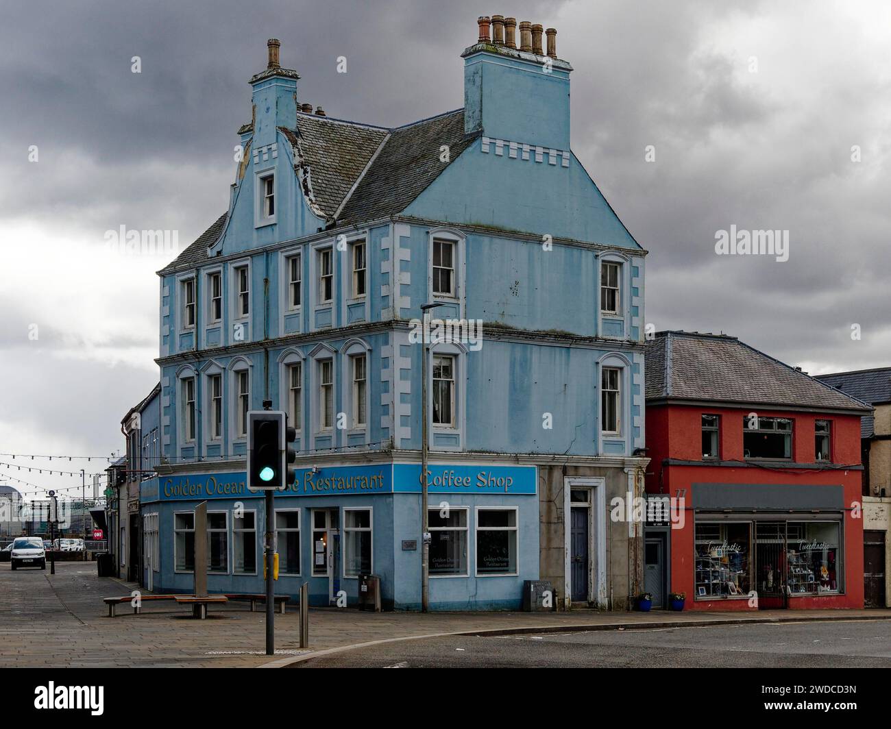 Pastel blue corner building with shops under a cloudy sky, Stornoway. Isle of Harris & Lewis. Outer Hebrides. Scotland, Great Britain Stock Photo