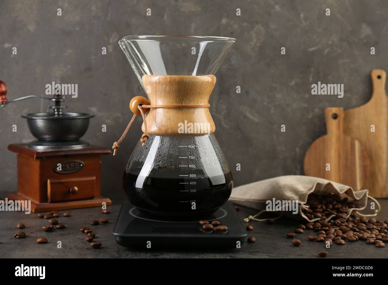 Making drip coffee. Glass chemex coffeemaker, beans and scales on gray