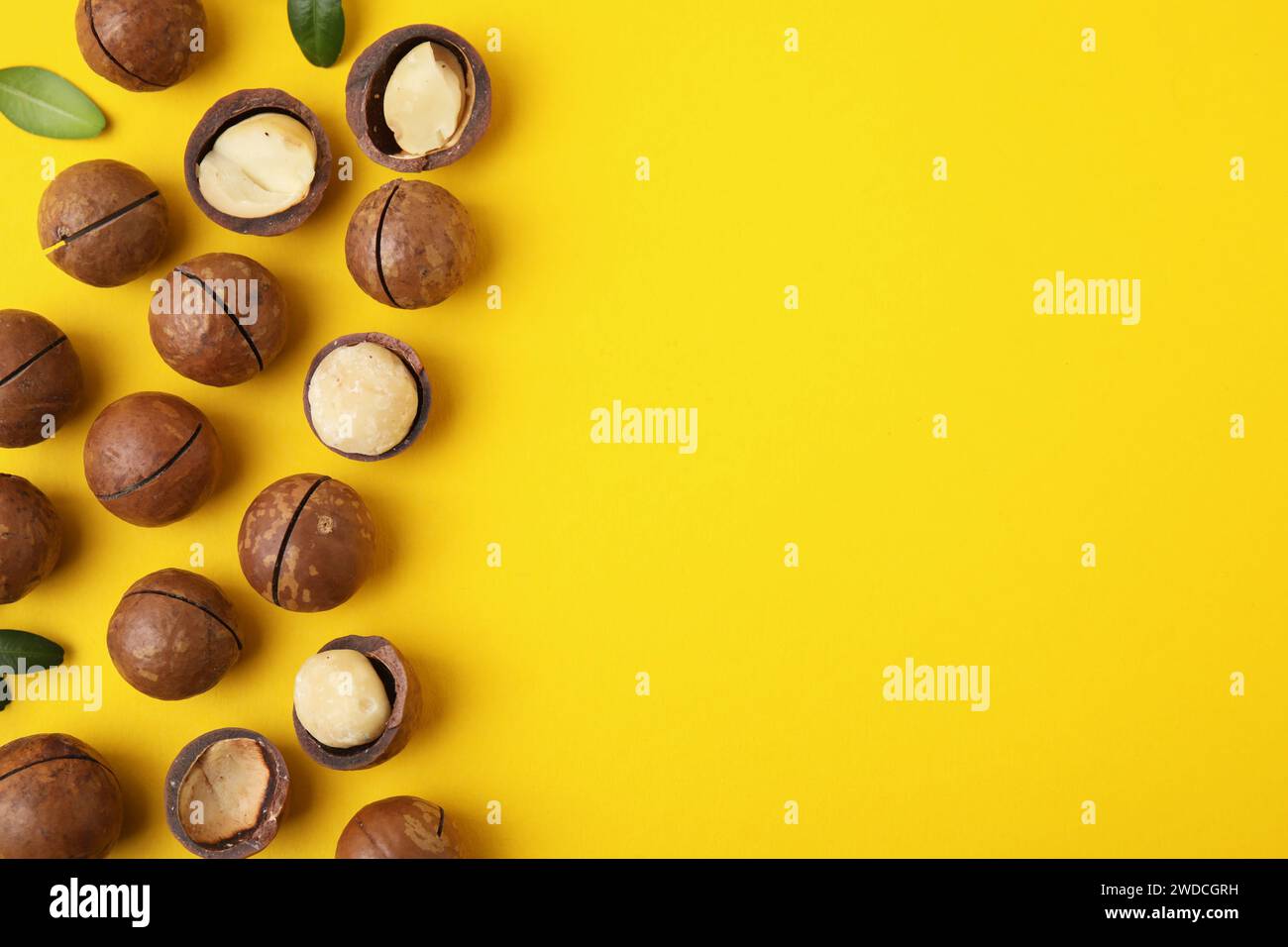 Tasty Macadamia nuts on yellow background, flat lay. Space for text Stock Photo