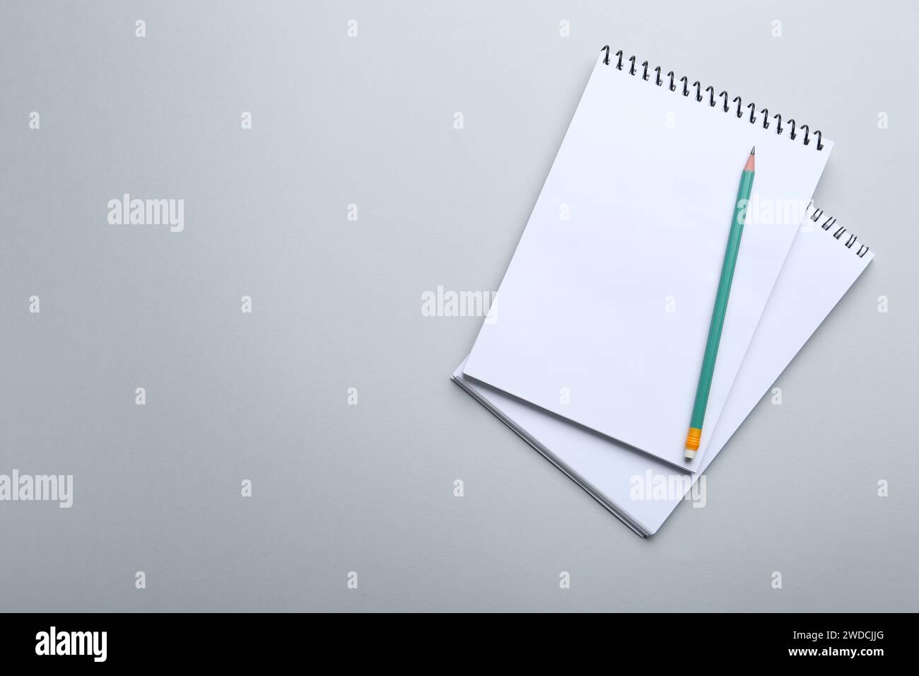 Notebooks and pencil on light grey background, top view. Space for text Stock Photo