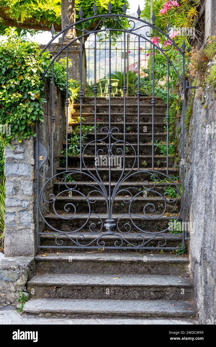 A closed wrought iron gate blocks access to steps leading to a private residence in Varenna, Lombardy, Italy. Stock Photo