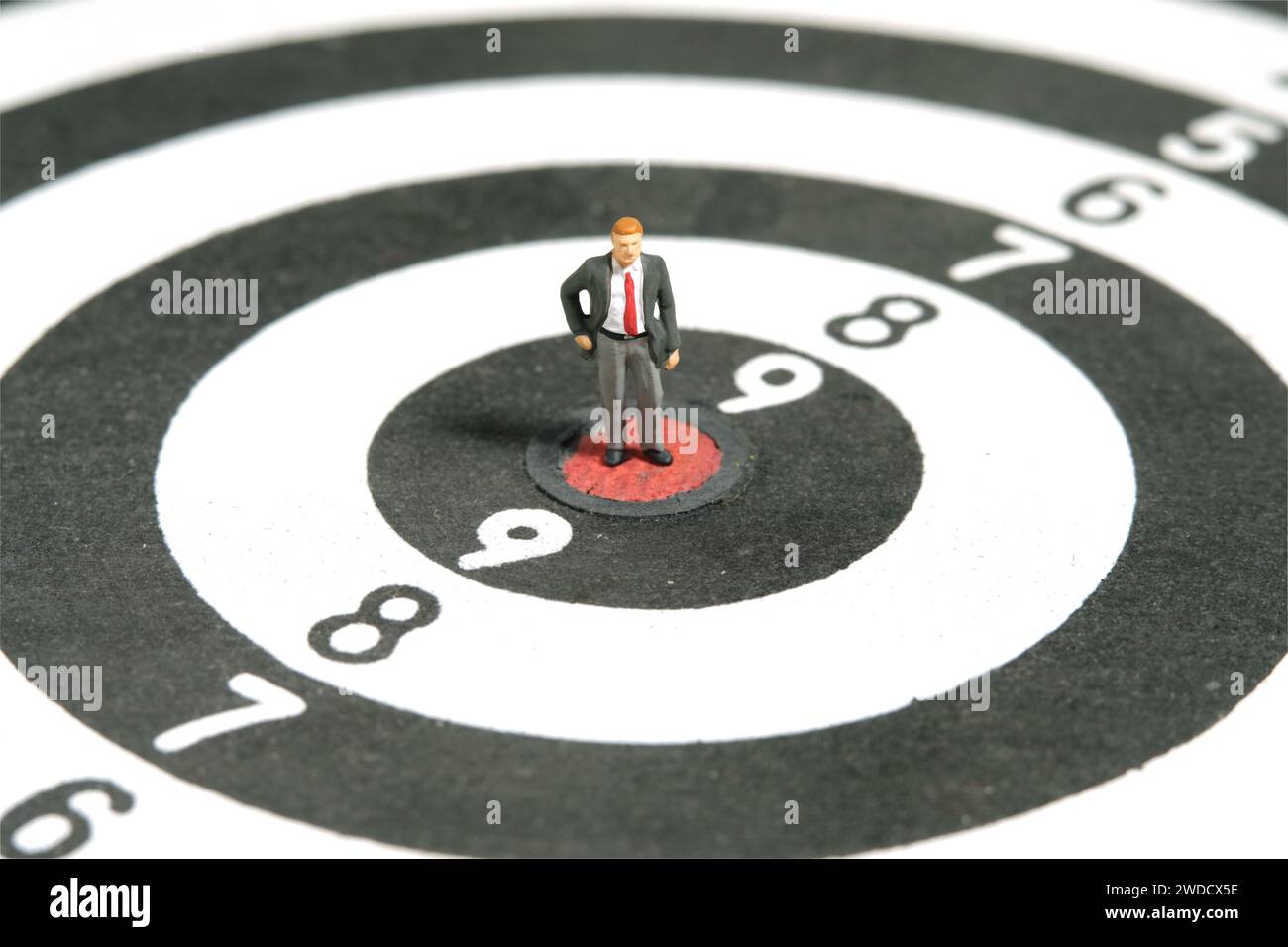 Miniature tiny people toy figure photography. Business concept illustration. A businessman standing at the center of dartboard, thinking and measure t Stock Photo