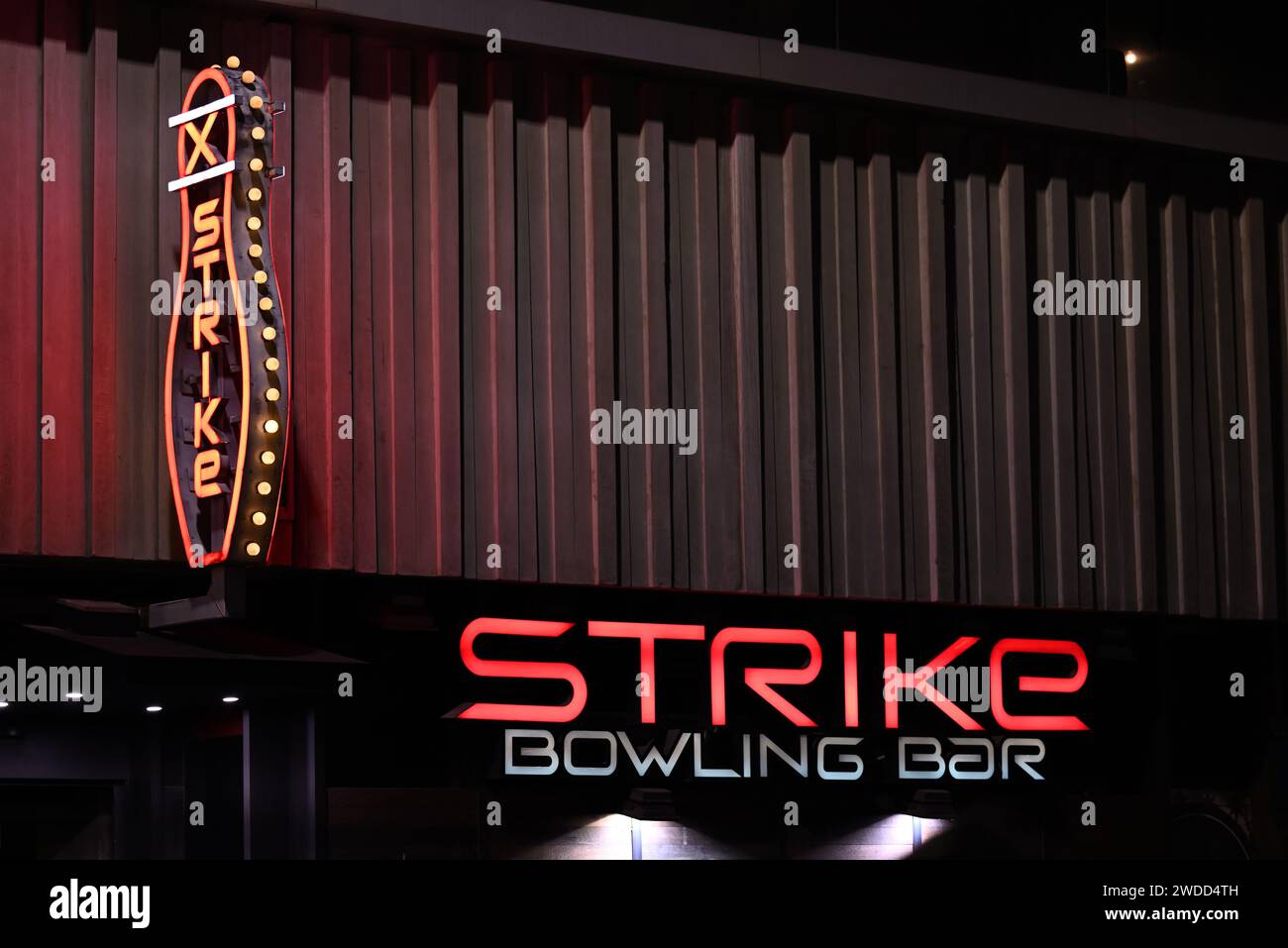 Predominantly red illuminated signage, featuring one sign resembling a bowling pin, outside Strike Bowling Bar at QV at night Stock Photo