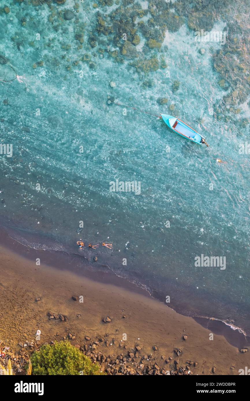 An aerial view of tourists bathing in the lagoon of a tropical travel destination. The water is turquoise and transparent. Etang Salé, Reunion Island. Stock Photo
