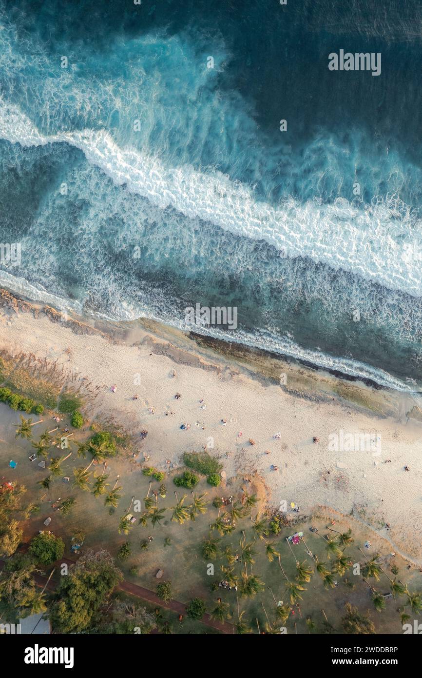 An aerial and scenic view of Grande Anse beach on Réunion Island. Palm trees and people enjoying the view of the sunset can be seen. Stock Photo