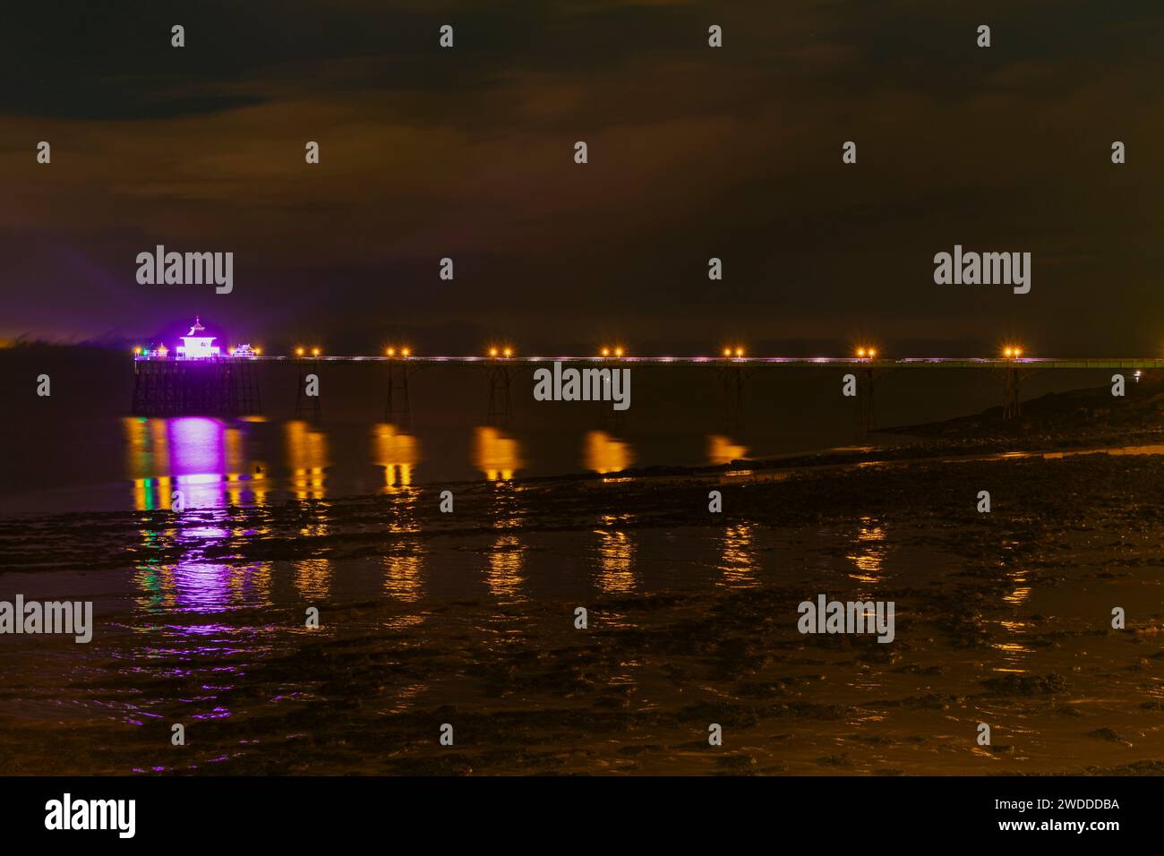 The coloured lights on the Pier reflecting onto the sea and mud Stock Photo