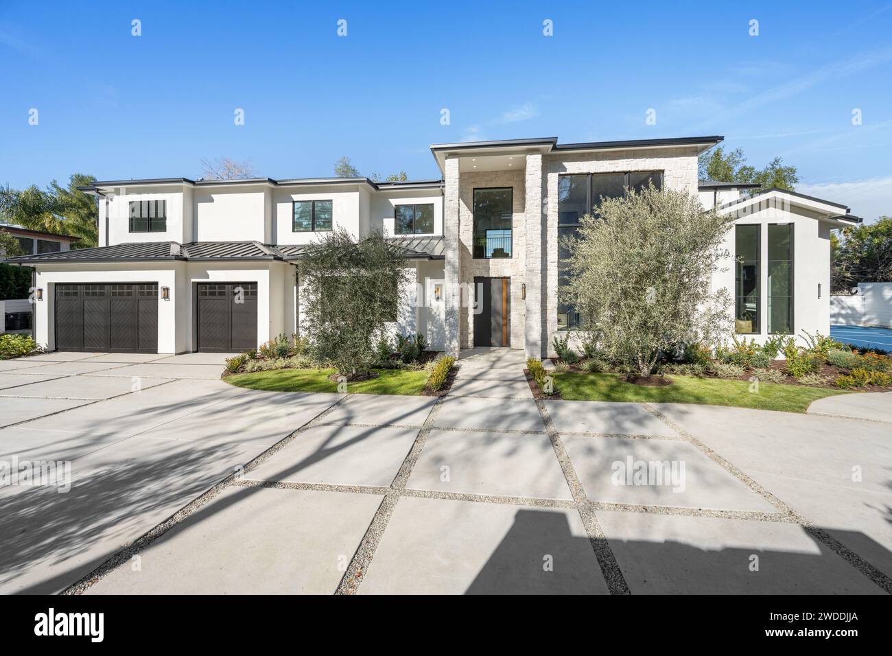 White contemporary house with wellmaintained landscaping in front of