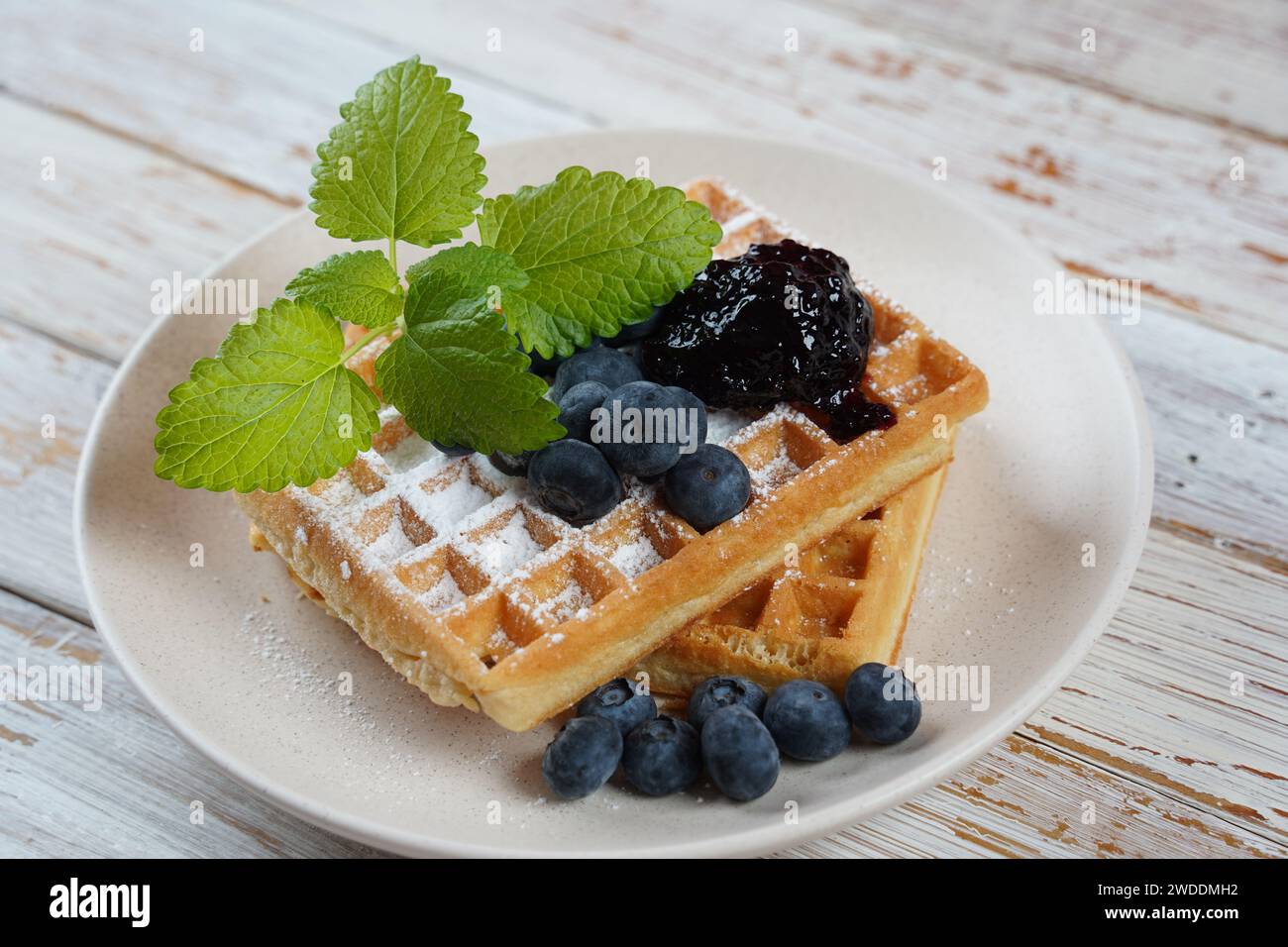 Delicious waffles with blueberry jam and fresh berries on wooden table Stock Photo