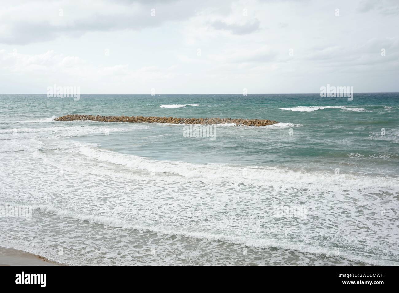 Strong currents and waves in the sea. Waves successfully crash into the stone breakwater. Stock Photo