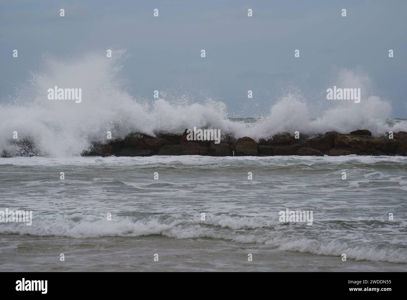 Strong currents and waves in the sea. Waves successfully crash into the stone breakwater. Stock Photo
