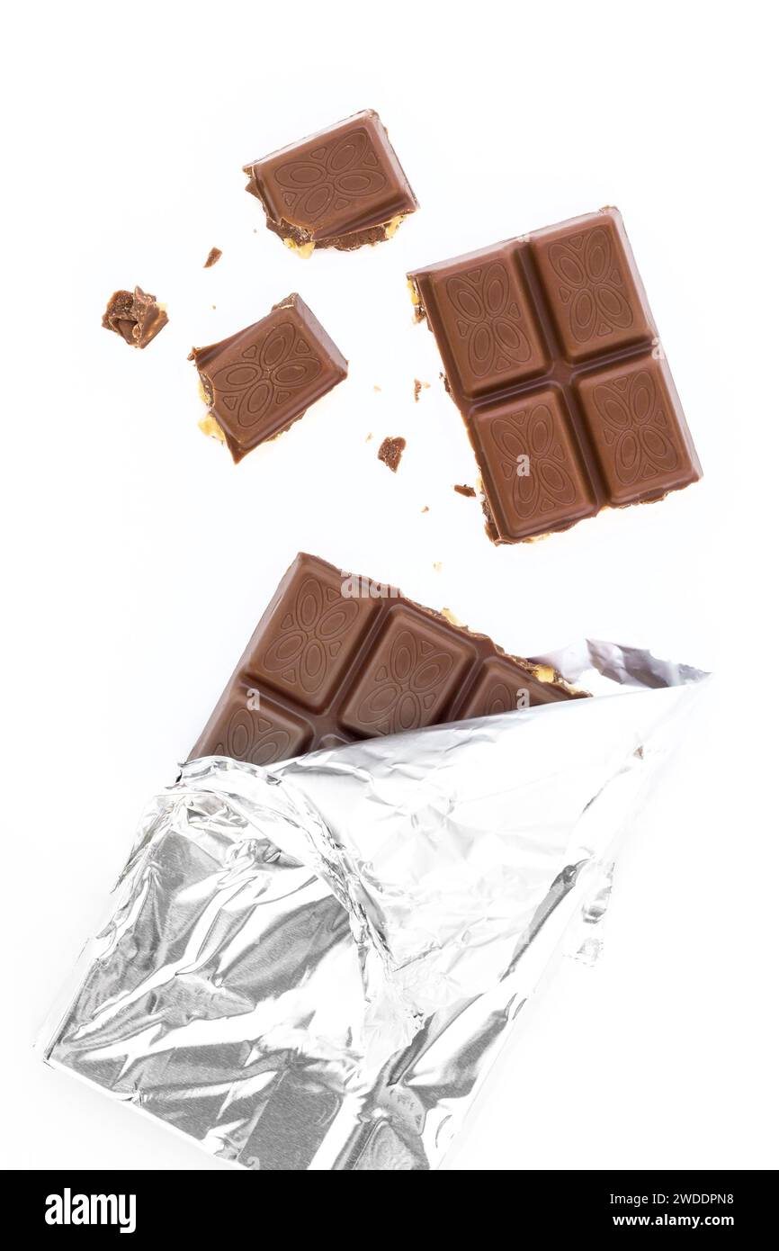 Bar of milk chocolate and almonds in a silver foil, partially unwrapped. On white background, pieces of chocolate. Stock Photo